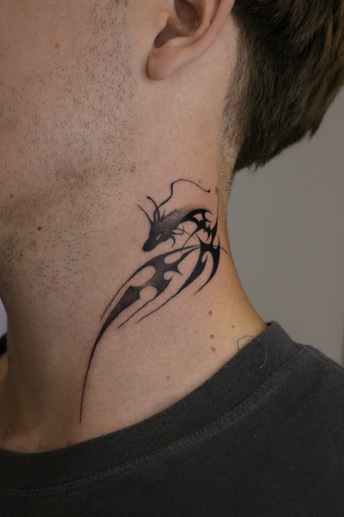 Close-up of an abstract dragon neck tattoo with black shading, sharp graphic lines and negative space, Prague by Andrey Kovalov