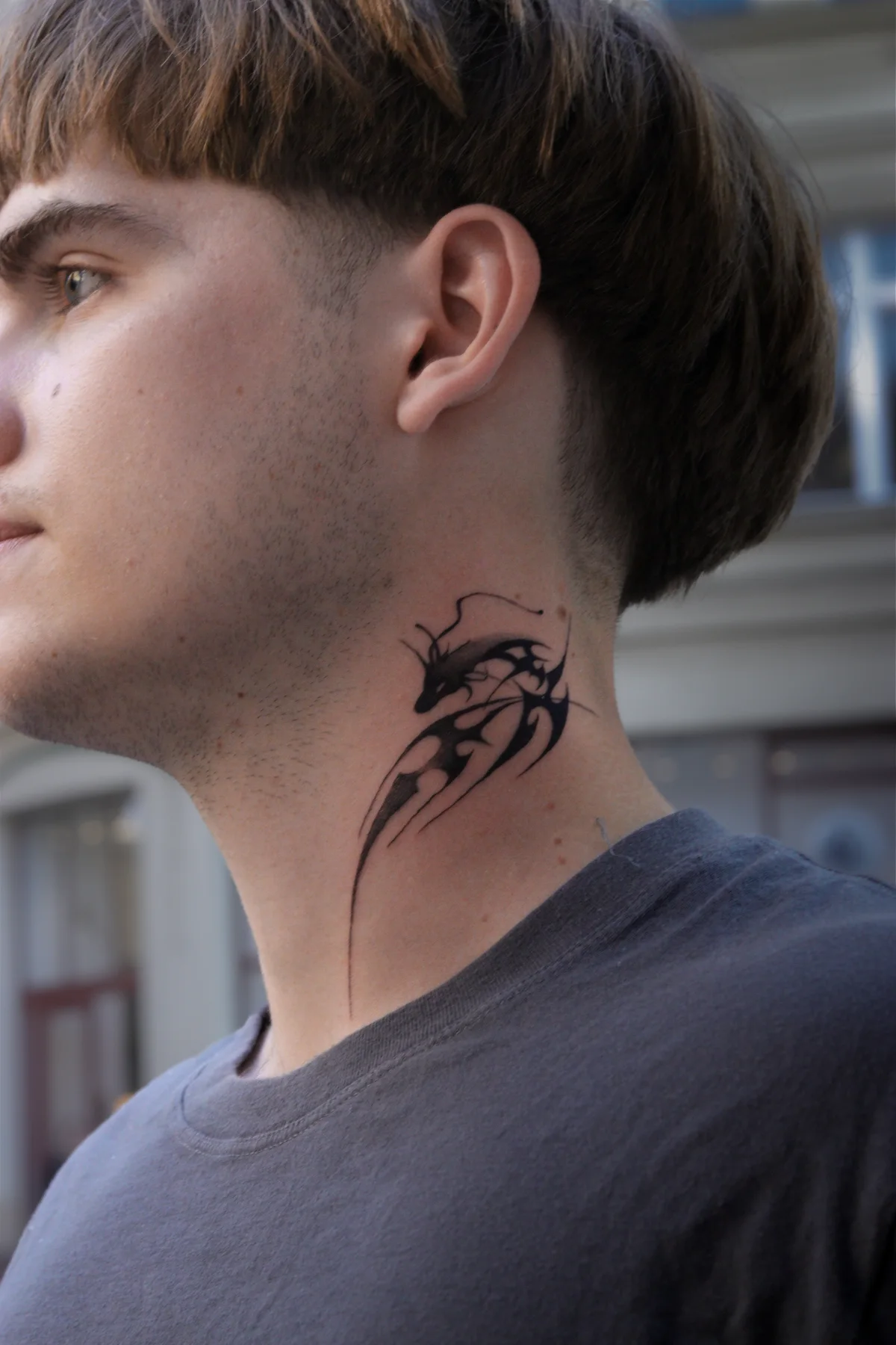 Graphic blackwork dragon tattoo on the side of the neck in Prague by Andrey Kovalov